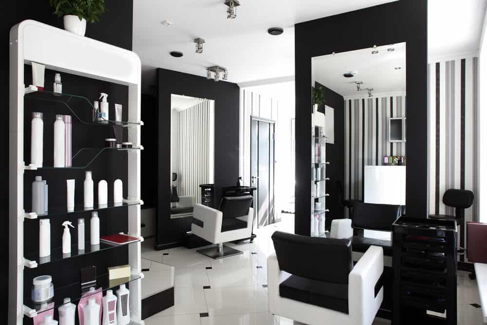 Crisp black and white salon really highlights the green of the plants and the pink and burgundy of the salon items. There is also grey in the striped wallpaper, and the mirrors open up the space and reflect the natural light. 