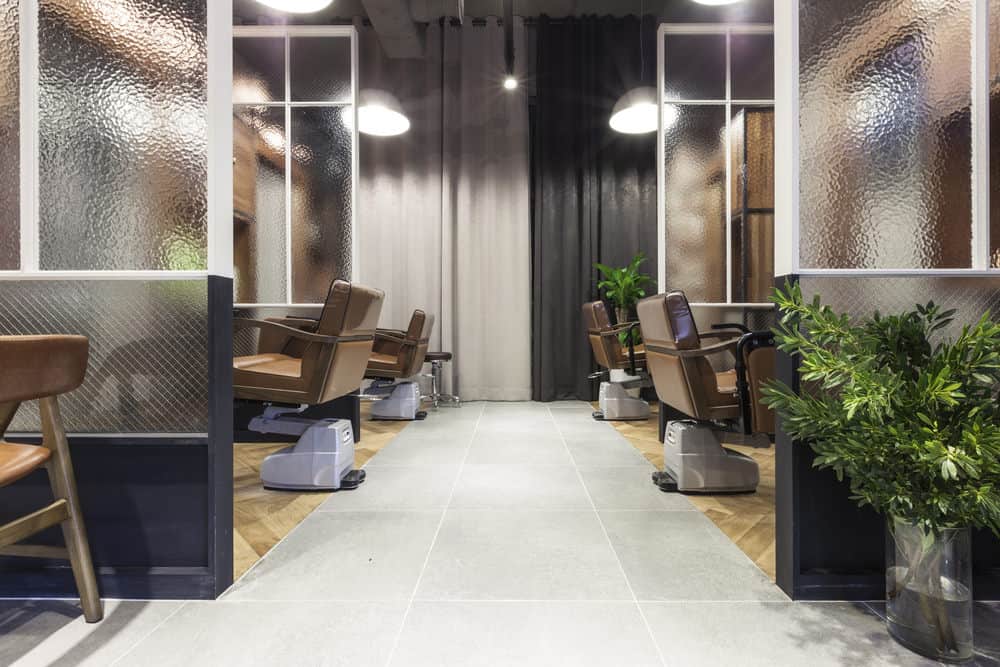 Metal pendant lights and black and white curtains balance the look of this salon, and the lush green plants create a relaxing Zen-like atmosphere. 