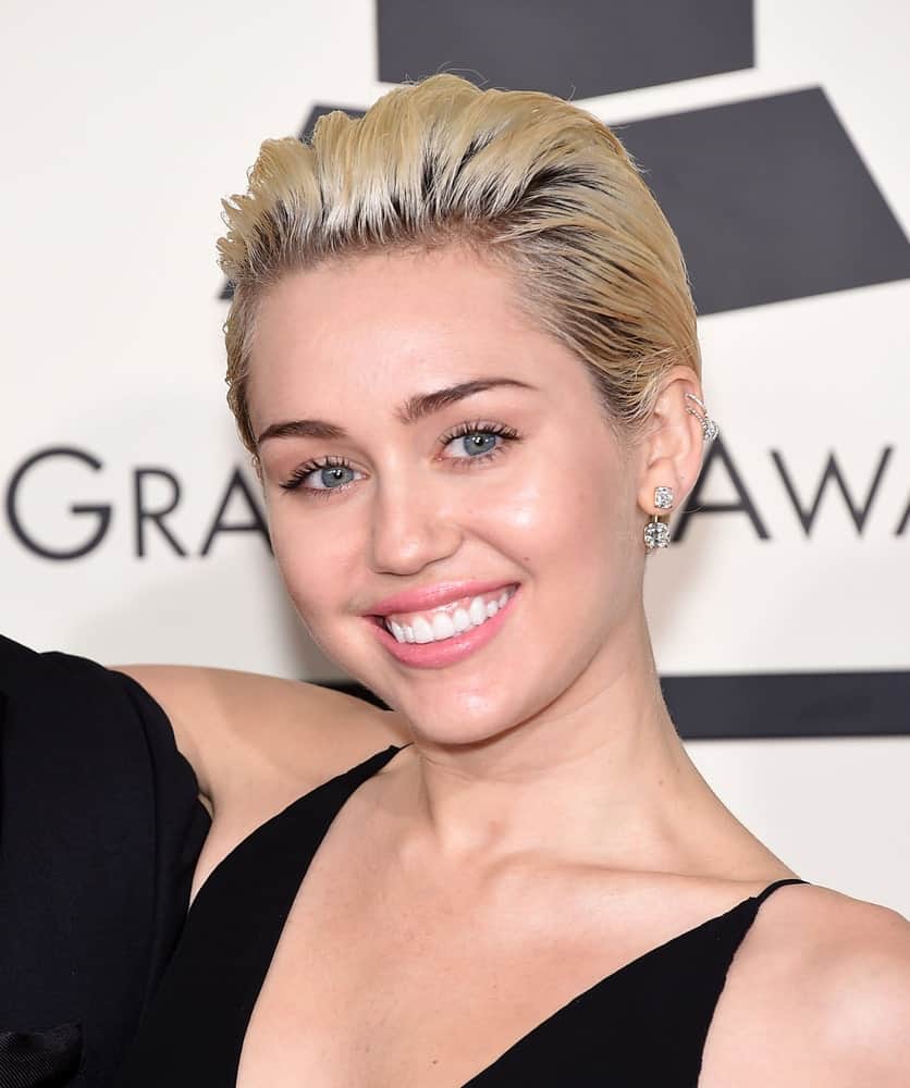Miley Cyrus sported a slicked back highlighted blond pixie hairstyle to pair with her sexy black dress and bright smile at the Grammy Awards 2015 on February 8, 2015 in Los Angeles, CA.