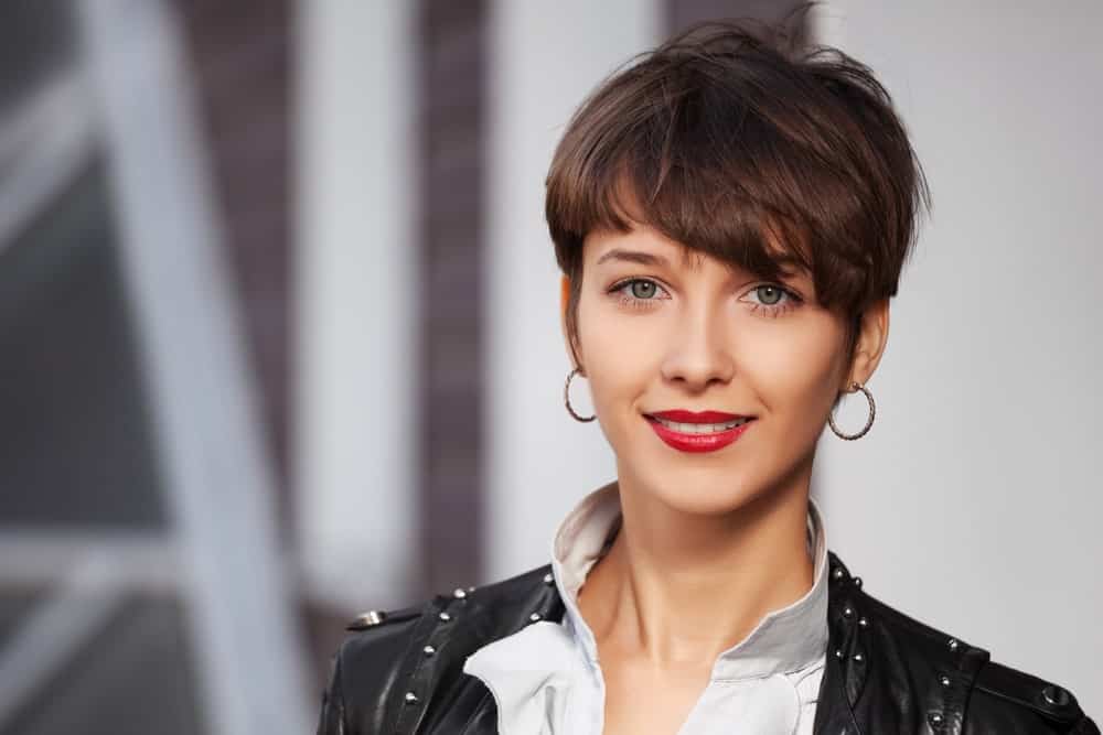 This young woman is sporting a classic pixie cut look. However, her side-swept bangs are a bit longer and almost touch her eye, giving her a super-hip look.