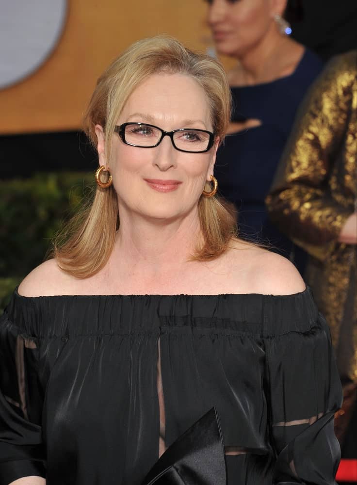 Modeled by Meryl Streep, this hairstyle is perfect for women over 50 who wish to show off their glasses in style. Shoulder-length hair secured at the middle in the back is the oldest hair trick in the book. The look is completed by a lock or two hanging loosely around the face to frame your glasses. 