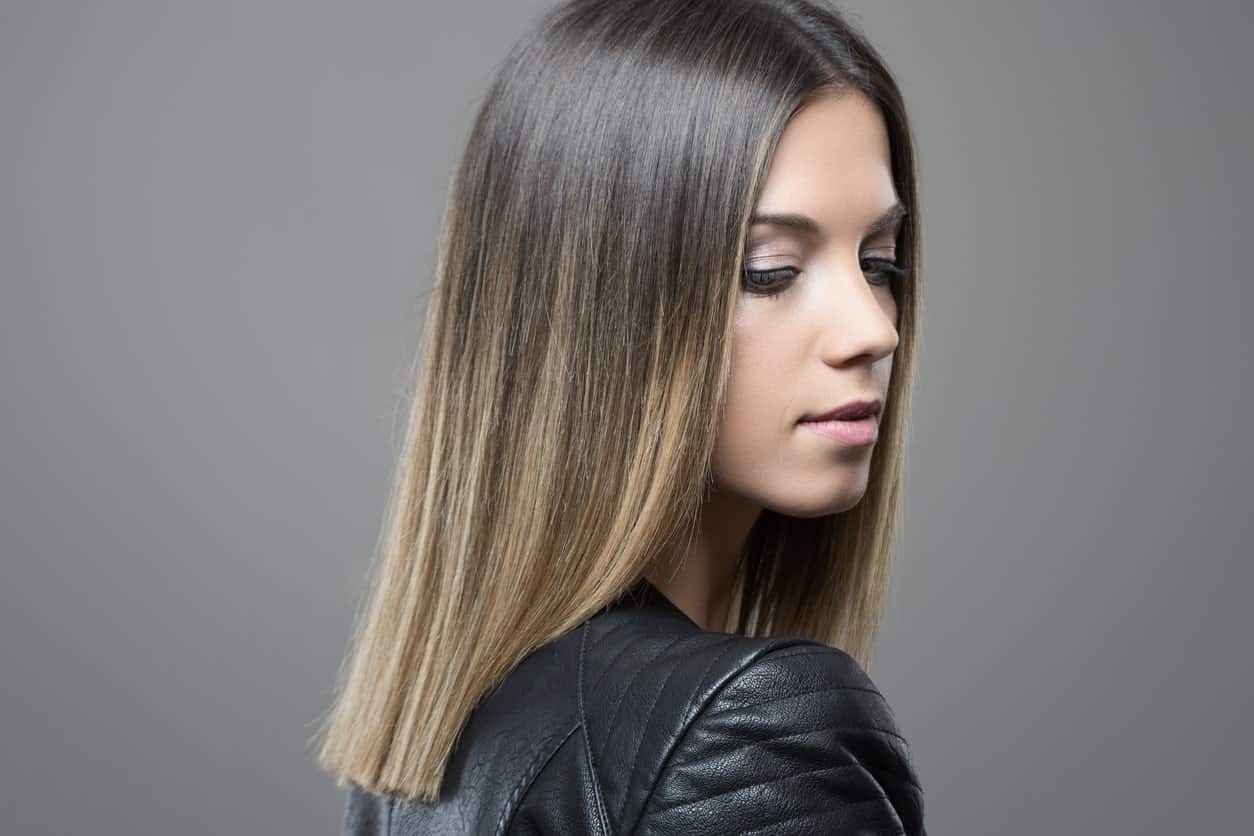 This stunning balayage starts from the young woman’s natural dark hair and graduates into several shades of blond, giving her hair a nude ash blond look.
