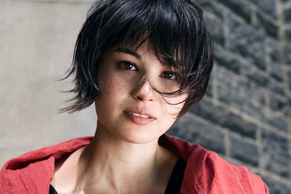This pixie haircut is coupled by a few wisps of longer hair on either side. This variant of the pixie cut gives this young woman a youthful, playful look.