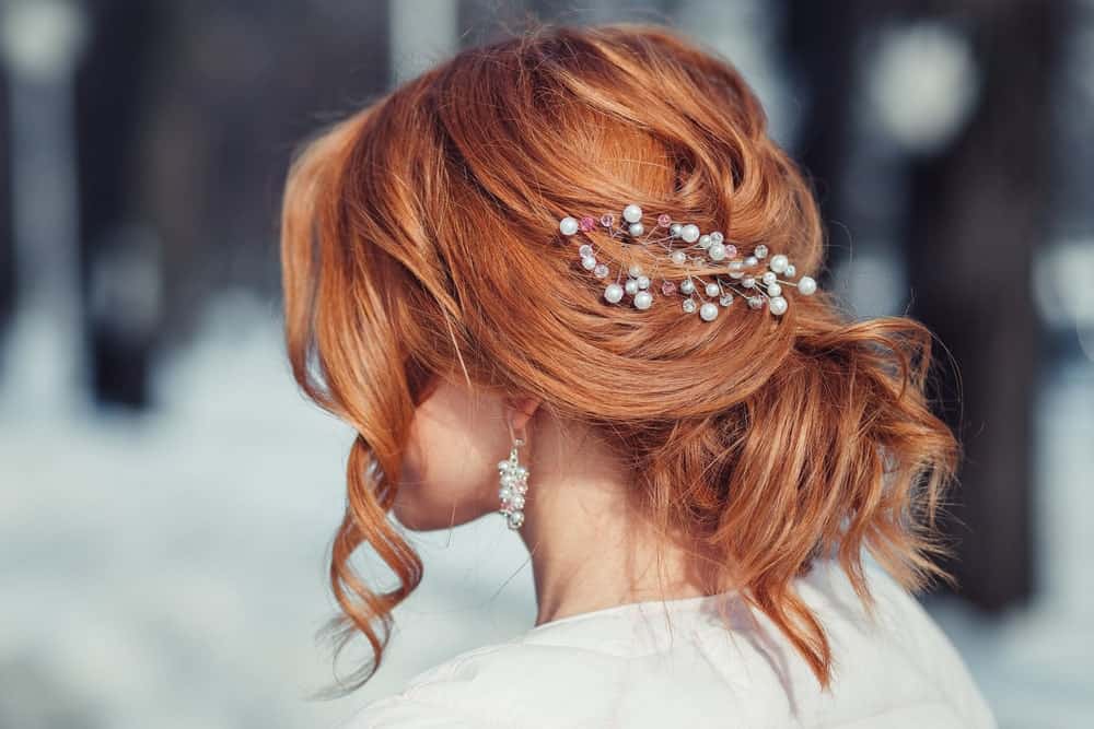 If you’re looking for a more formal hairstyle, consider this twisted bun with soft curls framing the face and a hair accessory to top it off. Pearly white and gray accessories go great with copper hair.