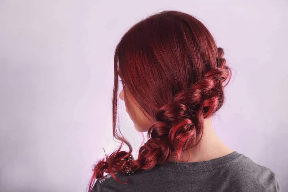 A thick, flowing braid down the side of your head is a great way to showcase the fiery undertones of the hair.