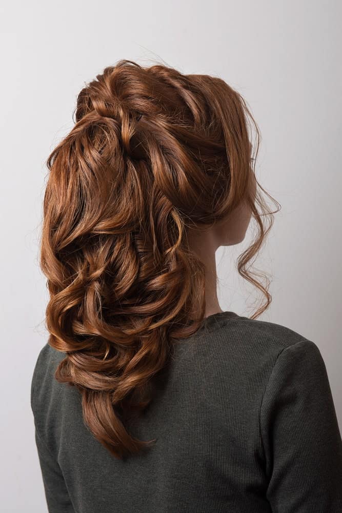 This hairstyle is a gorgeous option because it combines a little bit of everything. There are soft curly strands to frame the face, backcombing to add heights, pinned up twists for some interest, and gently cascading waves for a nice sleek finish. 