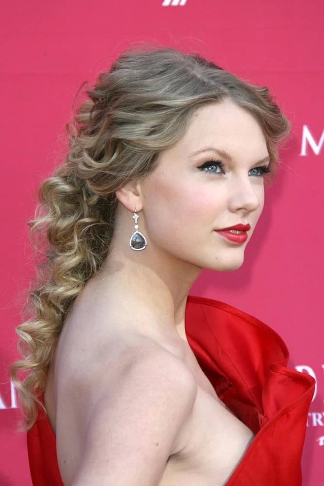 Taylor Swift adds a twist to a simple pinned back hairstyle by adding tight curls. It makes the hairdo seem more textured and more voluminous. 