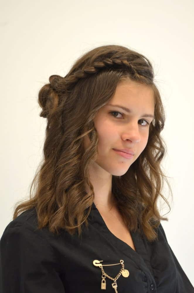 This youthful hairstyle uses the classic waterfall braid, but ends it with a twist by pinning up a small bun at the side of the head right above the ear. It works great with slightly curly hair because it will have more grip than silky straight locks.