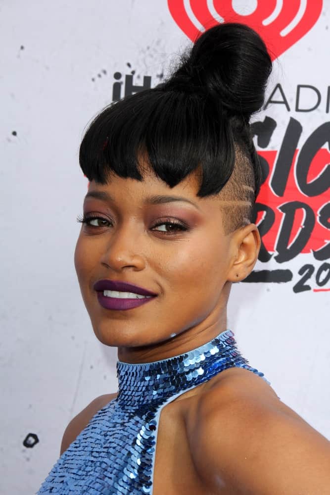 Keke Palmer is known for pulling off risqué looks. Her cool new hairstyle is achieved by shaving the sides of her head. The top and back part of the hair is pulled into a tight ballerina bun but the front part of her hair comprises of thick and pointed-cut bangs.