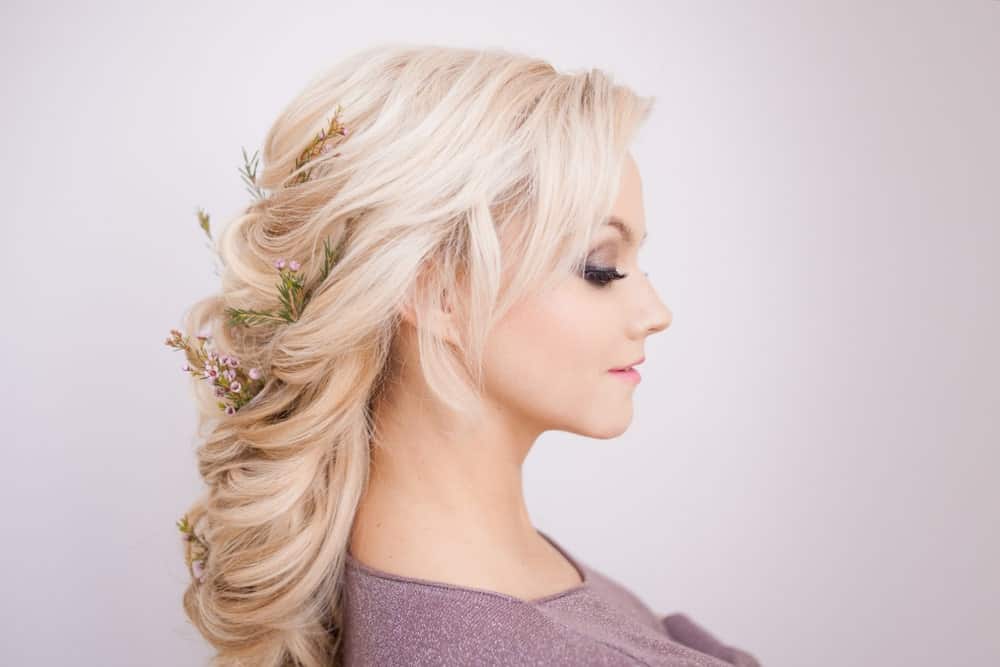 Soft curls are entwined with flowers to create this elegant, pretty hairdo. There’s a little bit of backcombing at the crown where the hair is pinned back but the rest of the locks are gently curled into one another for a soft finish. 