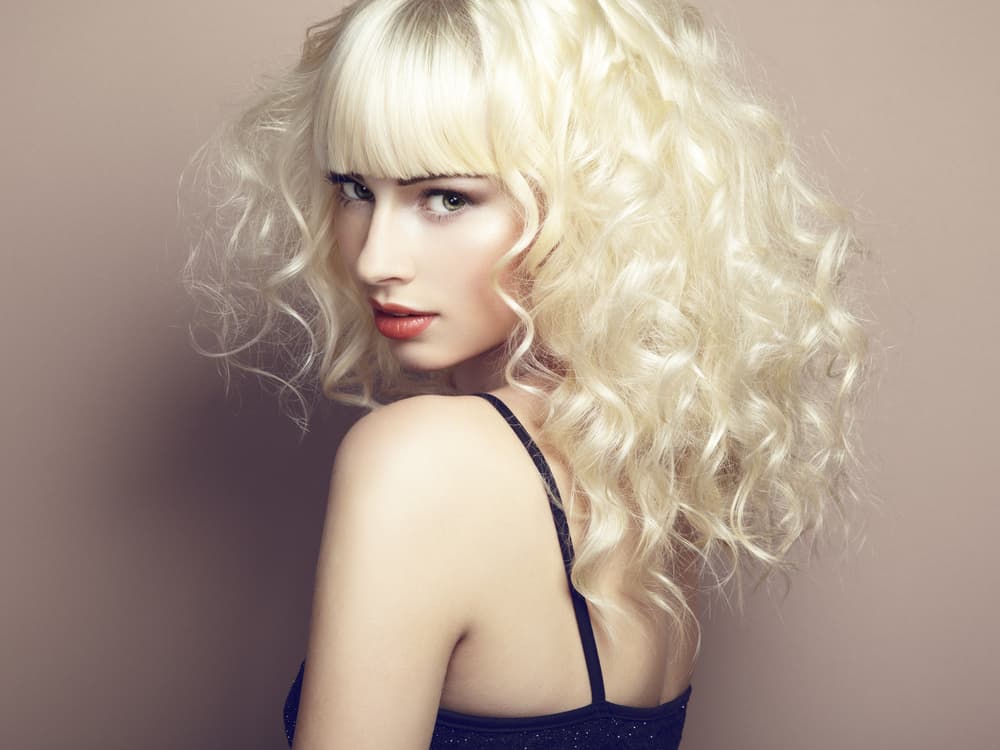 A model with platinum blond curly hair with bangs