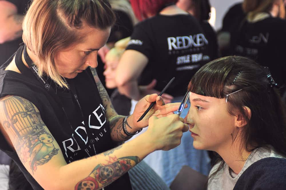 A Redken hair stylist cutting a model’s hair backstage at Mercedes Benz Fashion Week