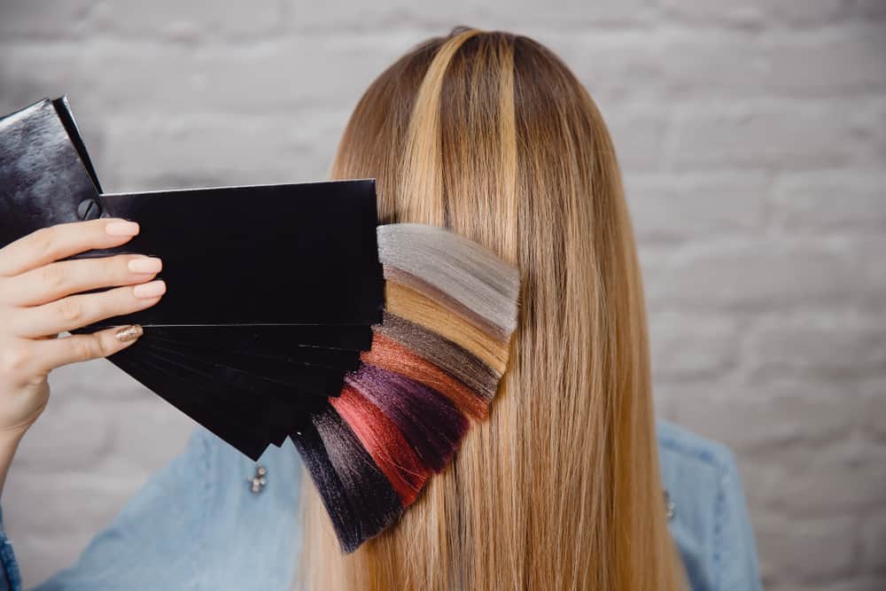 A hair stylist showing a palette of hair color behind a client’s head