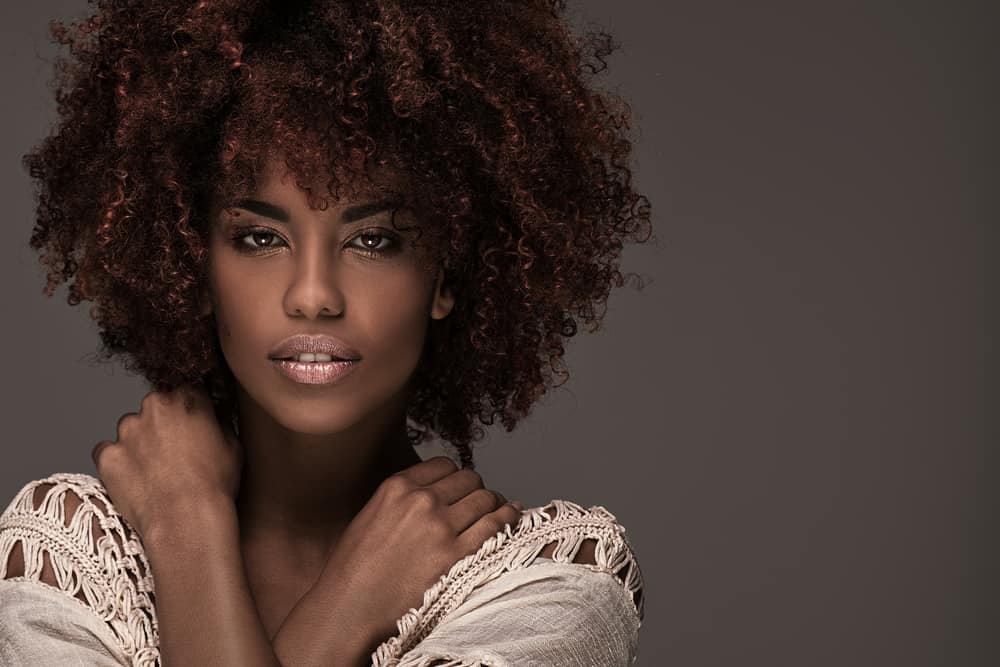 A model rocking an afro hairstyle and glamour makeup