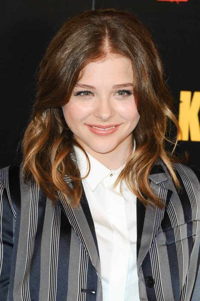 Chloe Grace Moretz attended the photocall to launch the movie, "Kick Ass 2" at Claridges Hotel, London on May 08, 2013. She wore a gray coat with her smart casual outfit with her shoulder-length brunette hairstyle with highlights and layers.