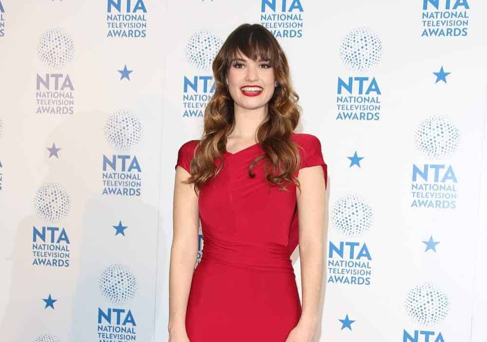 Lily James was in the winners' room at The National Television Awards (NTA's) 2013 held at the O2 arena, London on January 23, 2013. She wore a lovely red dress that pairs well with her red lips and long brunette hairstyle that has waves, layers, and long side-swept bangs.