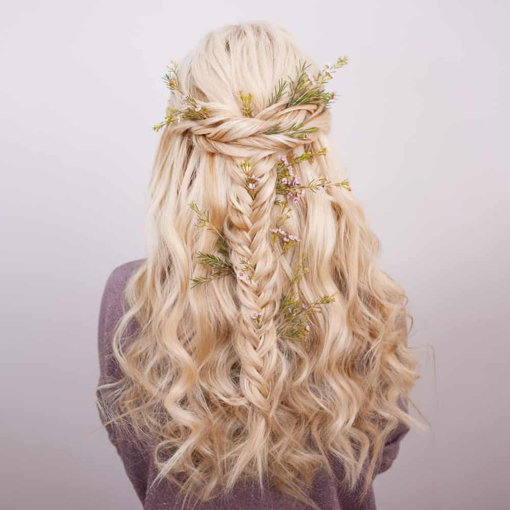 Bring out your inner “Khaleesi” with this ultra-awesome hairstyle for long curly blonde hair. If you are a fan of braids, you will love this hairstyle that features two styles of hair braids, one forming a crown at the back of the head while the other, which is a fishtail, adding texture to the hair and giving it a gorgeous look. To finish off the look, add a floral touch by decorating your hair with flowers. Whether you use fresh flowers or opt for the artificial ones that are specially designed for hair – it is a great way to take your hairstyle to the next level and add an X-factor to it!