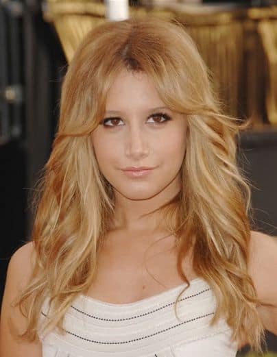 This is the famous Ashley Tisdale rocking a beautiful, blonde layered hairstyle with super short bangs-like layers on the forehead followed by long wavy layers all the way down.