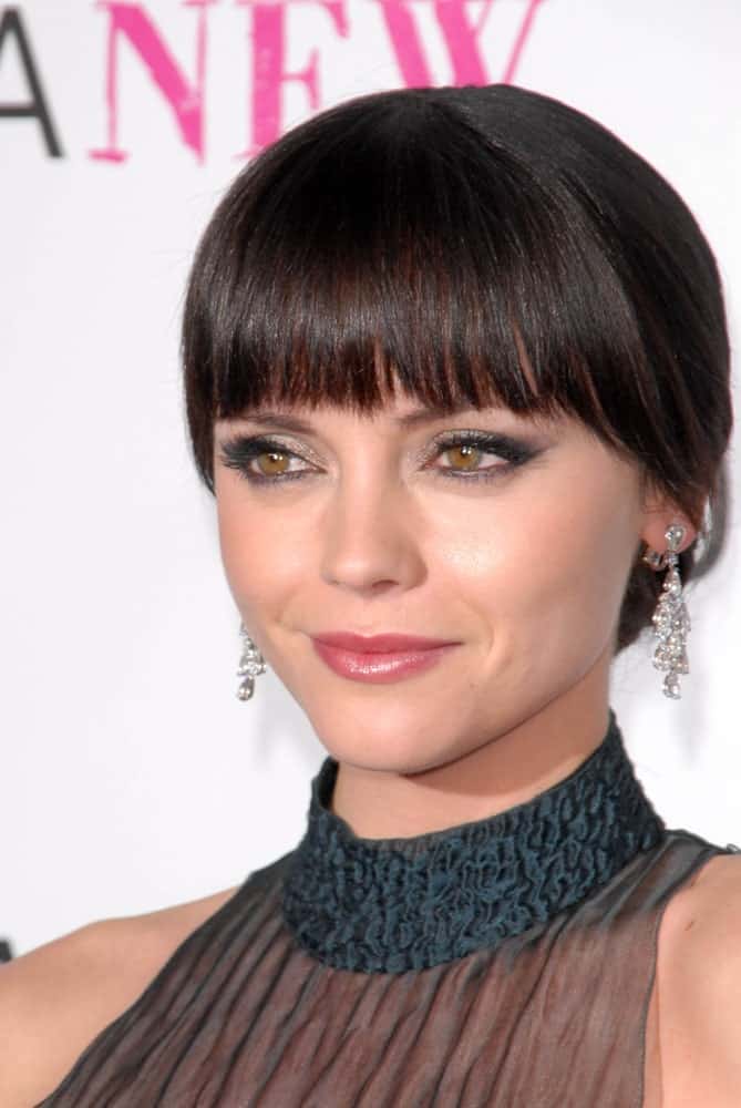 Here’s another hairstyle that you can sport without having to worry about swiping away loose strands of hair out of your face. Modeled by Christina Ricci, this hairstyle features blunt bangs. The rest of the hair is tied in an elegant low-bun at the back. If you are planning to complete your look with earrings, this hairstyle may be the right choice for you! 
