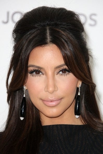 Here, Kim Kardashian has parted her bangs through the middle and swept them elegantly to the side. The rest of the hair is in free wavy curls while on top some backcombing has been done for a puffed up look. This is a great look for longer, slim faces.