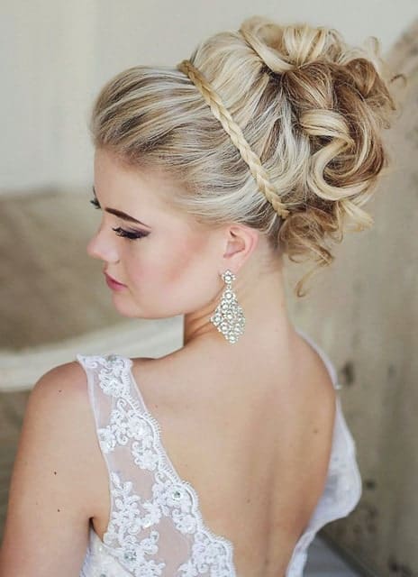 If you are going to a wedding, a great way to keep your thick hair off your face and neck is to style it up in an elaborate updo. Here, the model is sporting an updo with a braided headband and her thick curls pinned up in a classy updo.