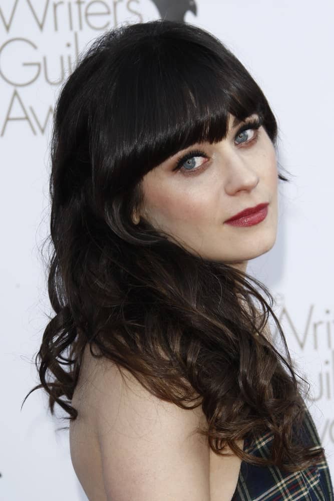 Zooey Deschanel is a true advocate of bangs. In fact, she has been sporting bangs for years! Check out this simple yet stunning hairstyle featuring blunt bangs and medium-length hair with loose curls. As the bangs frame the face from the top, the hair is casually tousled on the shoulder on one side, resulting in a subtle and natural look. 