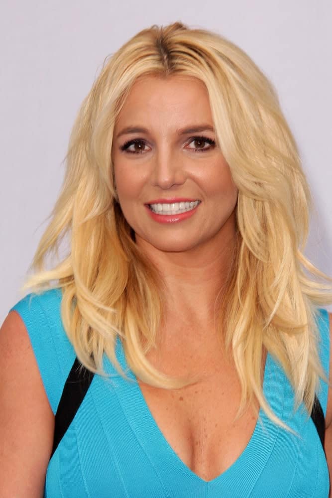 Here's Britney Spears with her famous blonde hair cut medium-length in 2013 layered and slightly wavy.  She's sporting a blue top.