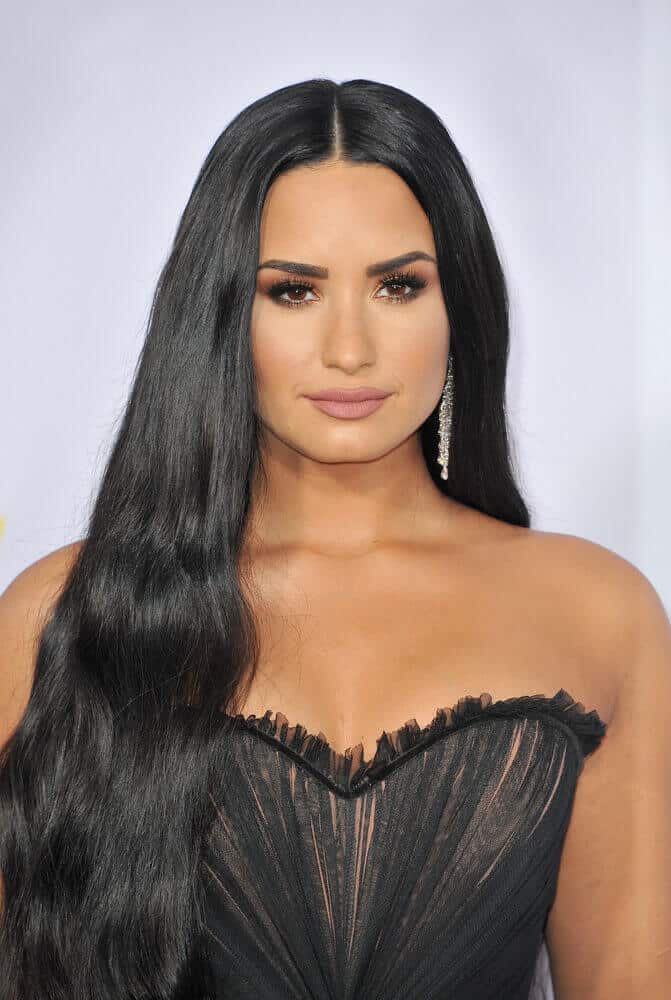 Demi Lovato is like a regal goddess with this hairstyle! Her center-parted, long and black hair is loosely set above her right shoulder. This one frames the shape of her face perfectly