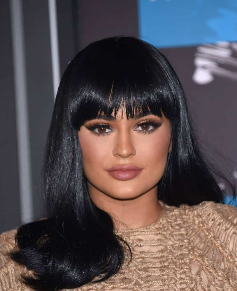 Kylie Jenner's thick black hair in a medium cut, paired with straight bangs. This hairstyle goes really well with dark, smokey eye makeup.