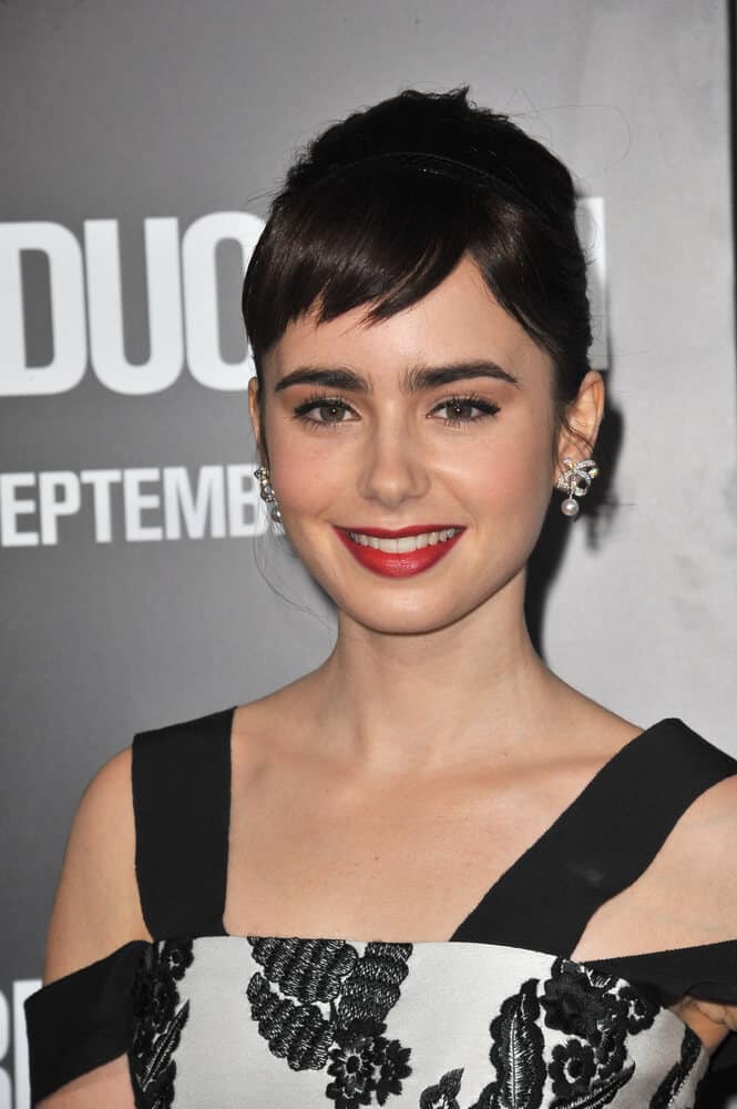The red-lip, classic look is Lily Collins' trademark! Her iconic look goes well with this retro upstyle with short, side-swept bangs.