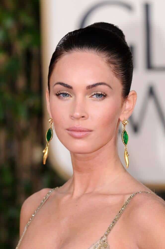 Megan fox looking extra elegant with her black hair styled into a sleek and tight bun, showcasing her facial assets.