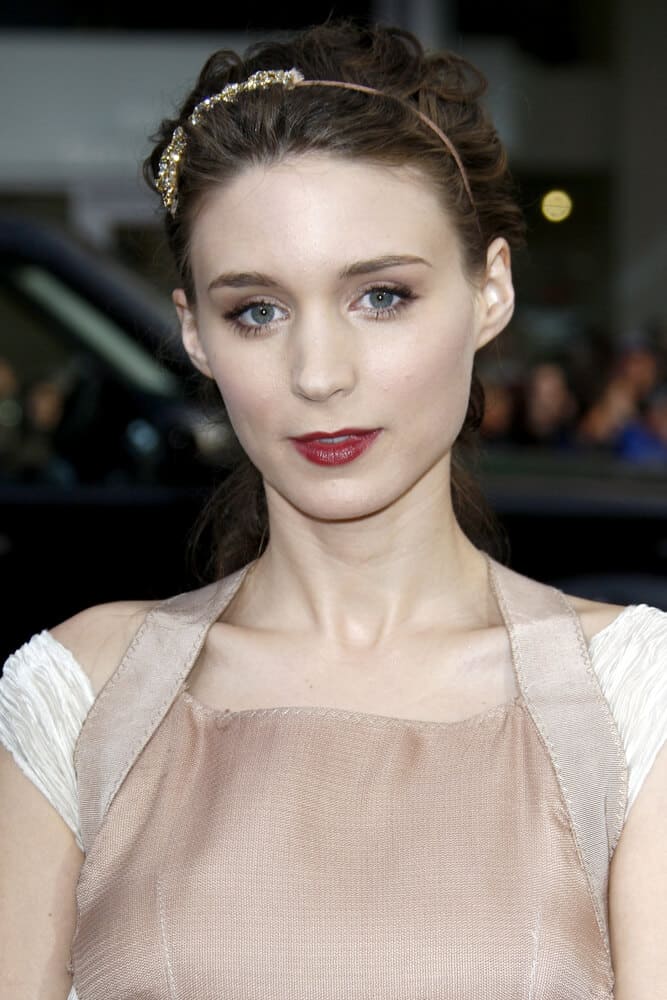 In 2010, Rooney Mara styled her curly hair into an updo embellished with a metal headband. The overall look is stylish and captivating!
