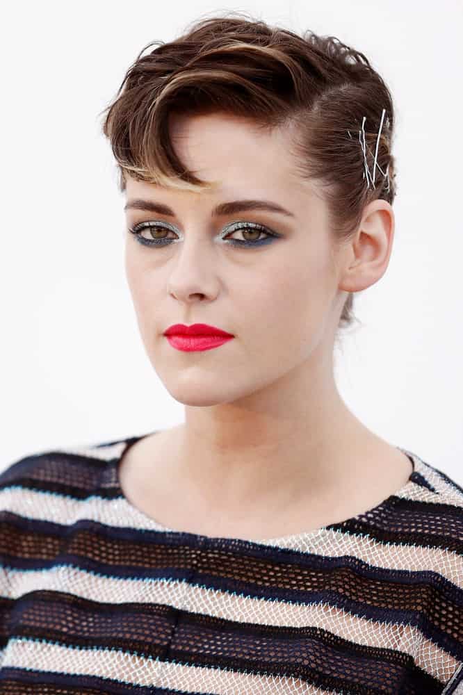 Kristen Stewart’s short hairstyle with highlights comprises of a neat pixie cut with slightly longer strands on one side. Notice how the tips of her hair have been dyed using a radiating gold color in order to shine brightly in her brown hair. A touch of pale blonde at the front further adds to the fascinating style. 