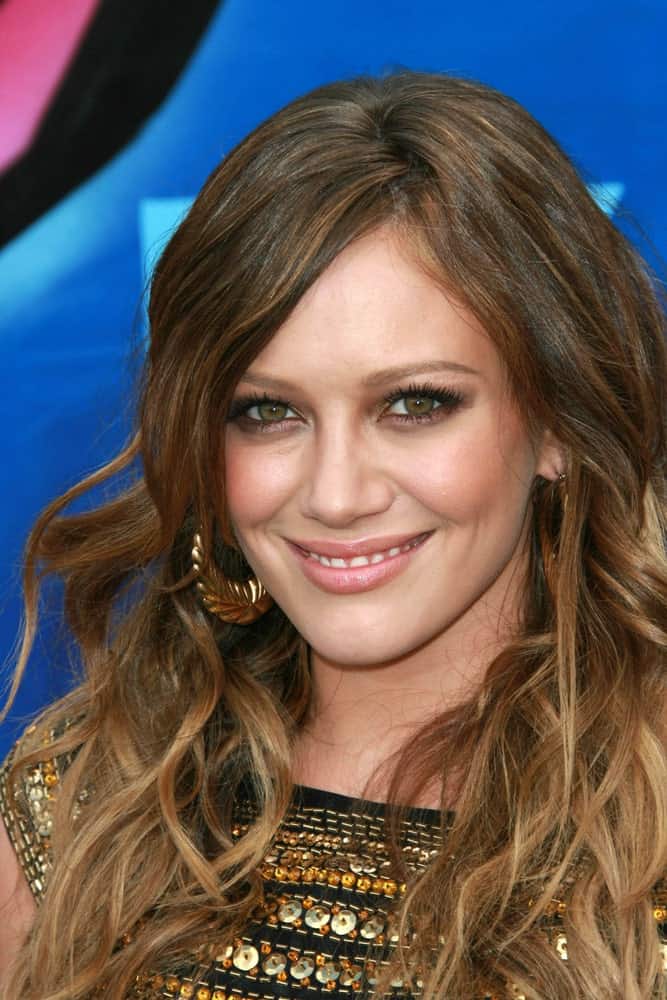 Wispy tousled strands that feature a spectrum of brown and dull brown shades make Hilary Duff look chic in this trendy hairstyle for women with curly hair. 
