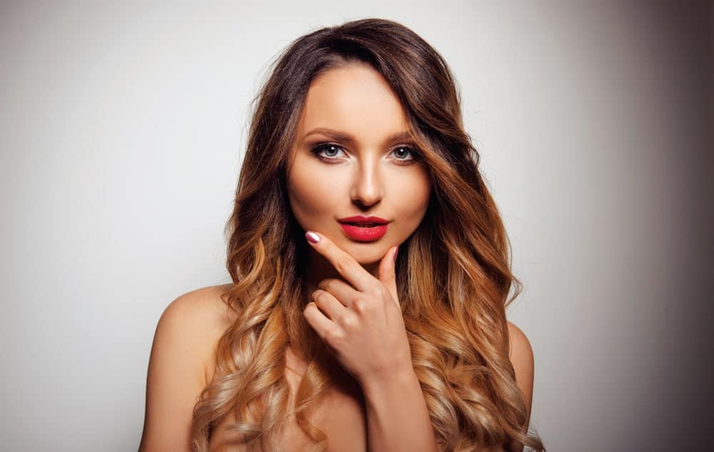 This highlighted look includes dark brown hair at the crown followed by curls of honey-ombre highlights.