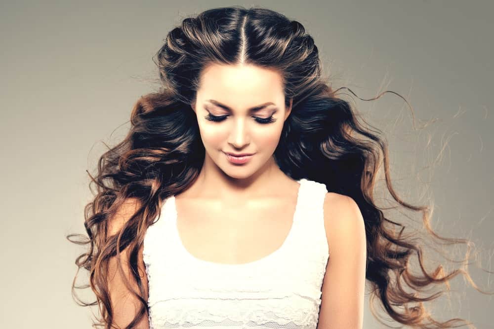 For a dramatic hairstyle, start with a center parting and carefully backcomb either sides of the hair at your temples. Spray with some hairspray and carefully pin them back. It’s going to add height and volume to your hair and make your hairstyle look much fancier than it is!