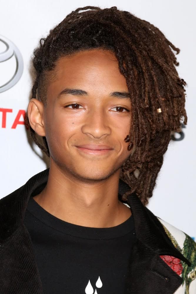 For anyone trying to experiment with their dreadlocks, this is the perfect style for you! This is Jaden Smith, giving you the ultimate bold dread-goals. He has almost shoulder-length dreads that he has pulled all the way towards a single side. The dreads appear to be piled up on top of the head, giving the hair dimension and elevation. 