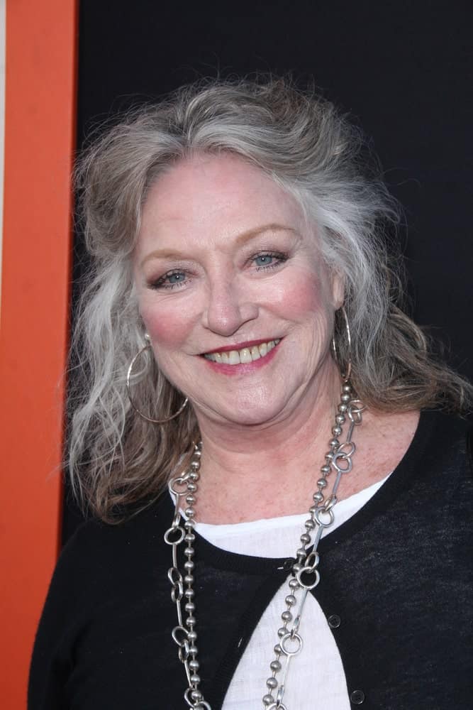 This ‘organic’ hairstyle sported by Veronica Cartwright is au naturel in every sense. Not only do we see the patches of gray in her dull brown hair, but she hasn’t spent much time in styling it either. Instead, she has simply clipped back a few locks to create this easy-going half-up-half-down hairstyle that looks impressive despite the simplistic approach. 