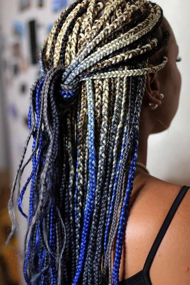 To achieve this stunning blue-and-gold Fulani hairstyle, incorporate multi-colored threads into your braids. Ask your stylist to make very thin plaits in your hair and incorporate them with pale gold, royal blue, and earthy-brown threads. Then pull the braids back from your side and crown and knot them at the back of your head to create a half-up, half-down style.