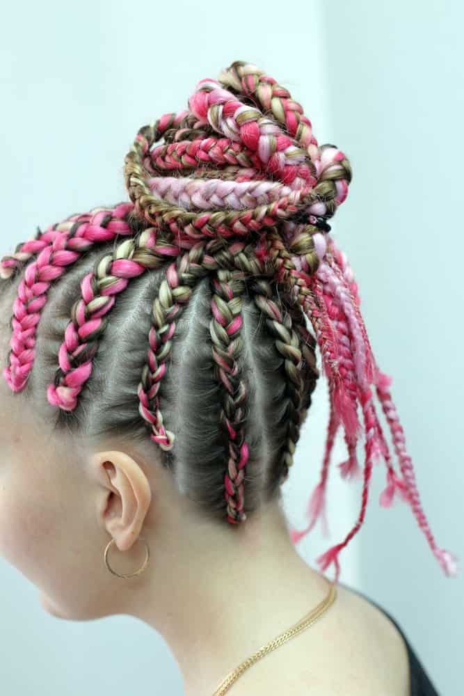 Pink is the color of the Millennials so why not incorporate it into your hair as well? For a more statement look, ask your stylist to paint your hair in various hues of pink instead of just one shade. Then add more pink thread and weave your hair into simple Fulani braids. To keep your dangling locks away from your face, twist them into a cool topknot.