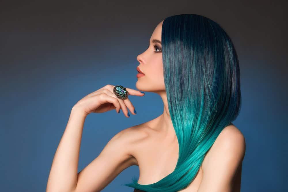 Jewel tones hair colors are trending with the masses these days, Here, this model sports a beautiful ombre which starts with a very dark green emerald tone at the top and graduates to lighter jade green color from the middle to the end. This is a perfect mermaid hair look.