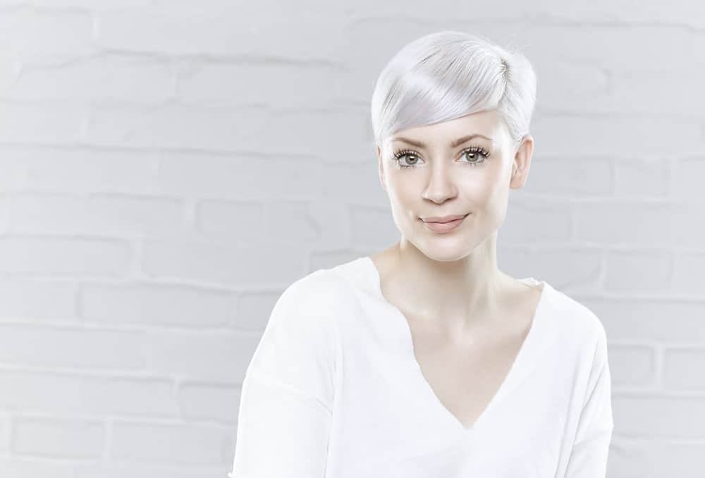 Here is an example of another super-short hairstyle; however, this one features longer hair in the front that is styled in adorable slanting bangs across the forehead. The shiny white hair puts the wow factor in this style. This is a great look for those who want to highlight their eyes and jawbone. The side swept bangs with a pixie cut also takes years off one’s face.