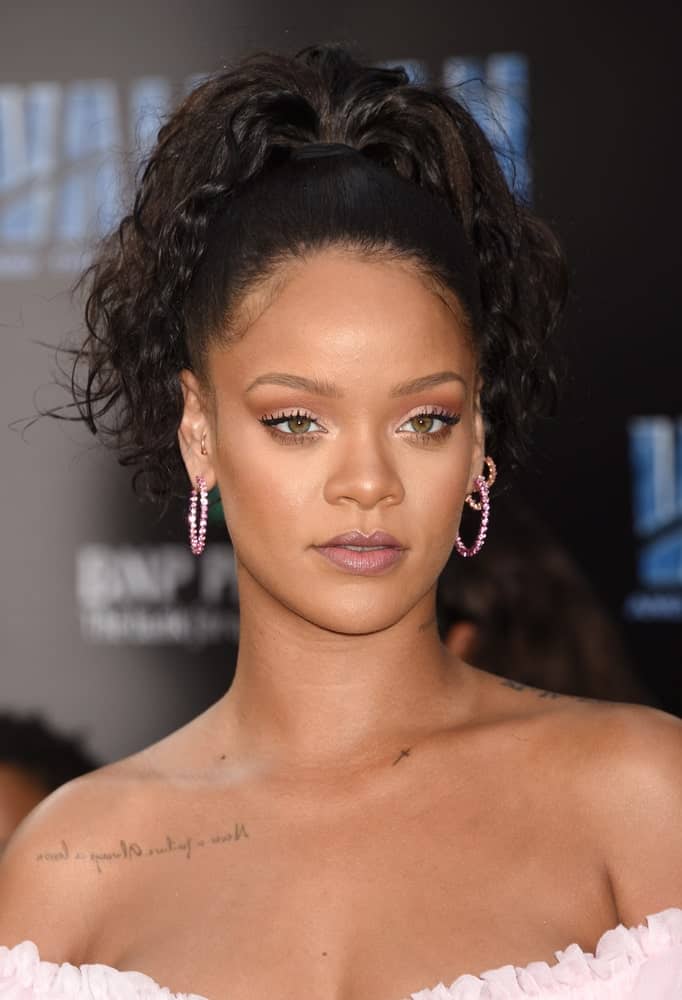 Rihanna’s high fountain-style ponytail is a smart way to let curly hair take center stage. The gorgeous jet-black loose curls falling onto her shoulders make her look super stylish besides emphasizing her face structure even more. 