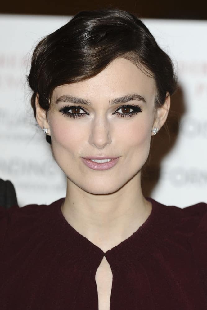 Keira Knightley attended the premiere of "A Dangerous Method" at the Mayfair Hotel, London on January 31, 2012. Her dark maroon dress was paired with a slick side-swept hairstyle with long side-swept bangs.