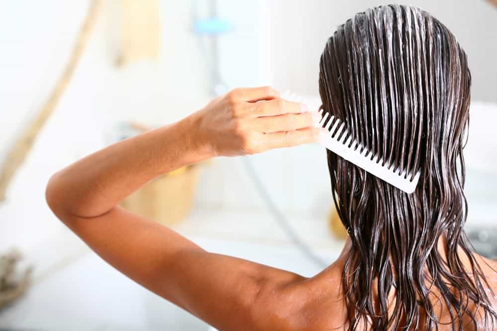 A woman applying hair conditioner to her wet hair