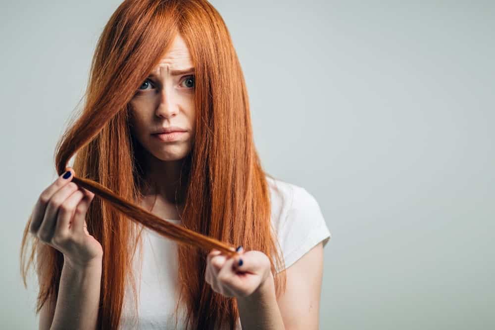 Woman looking troubled with her long red dry hair.