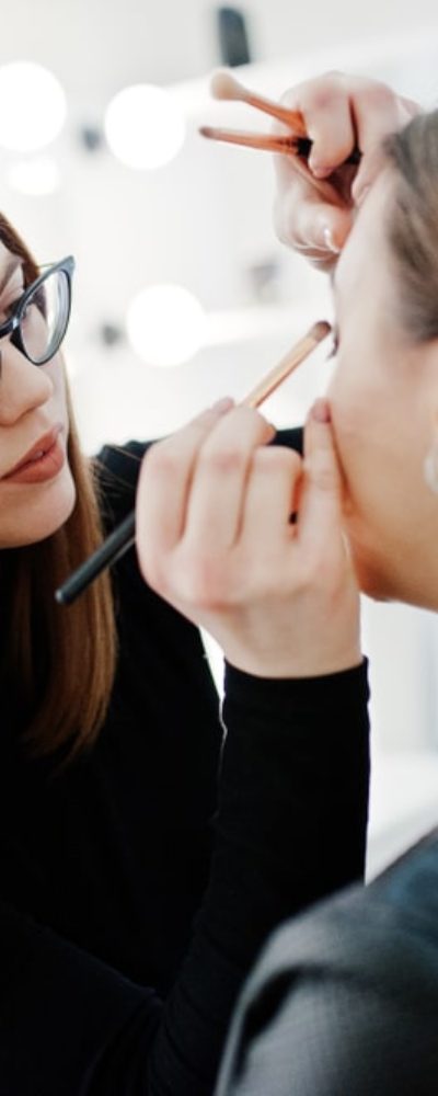A makeup artist applies eyeshadow on a woman.