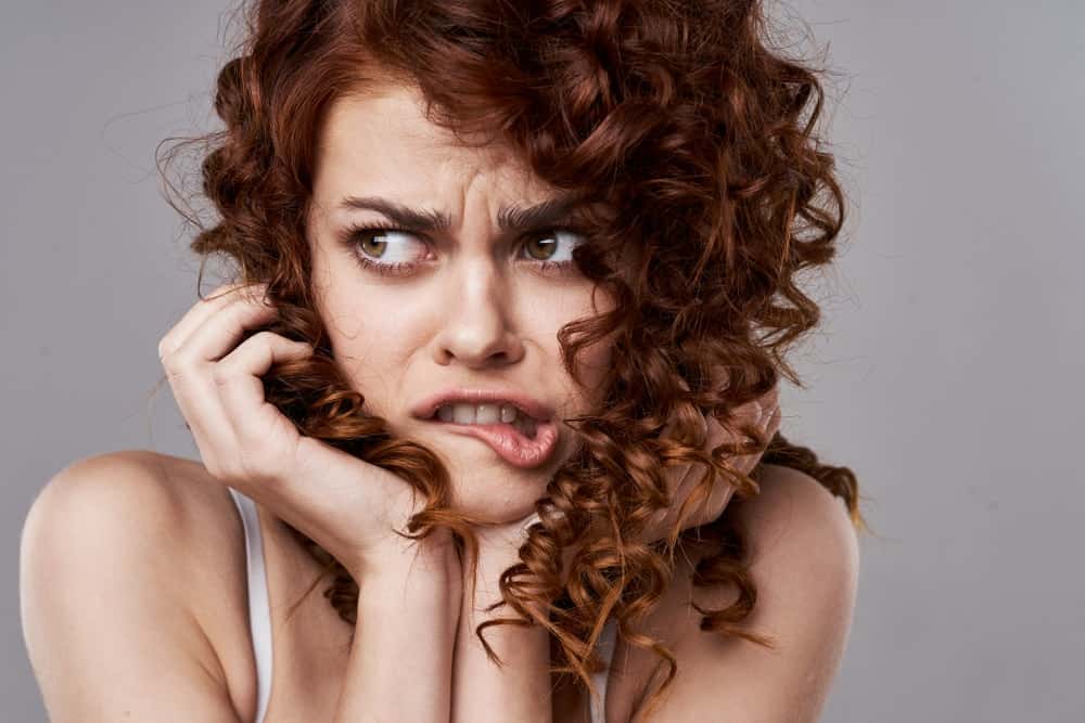 Curly-haired woman looking scared.