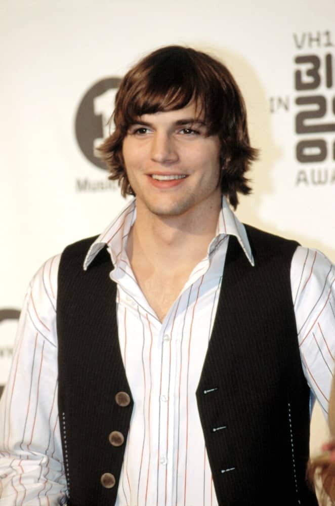 Ashton Kutcher attended the VH1 Awards on December 15, 2002 in Los Angeles, CA. The young actor wore a vest over his button-down shirt and topped it off with a side-parted long dark brown hairstyle with a flippy finish.