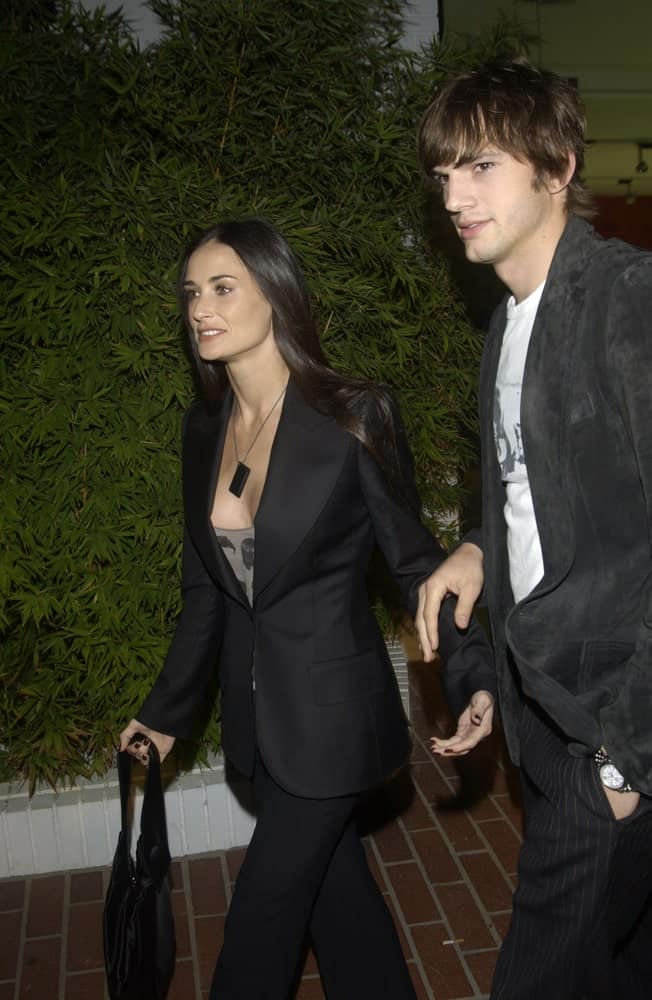 Demi Moore and Ashton Kutcher wore matching smart casual clothes at the opening of designer Stella McCartney's first Los Angeles store on September 28, 2003. Kutcher paired this with a tousled and wavy fringe hairstyle.